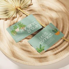 two business cards sitting on top of a wooden plate next to an orange and bamboo fan