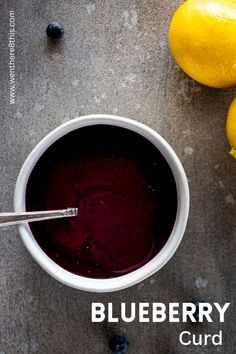 a bowl of blueberry curd next to lemons