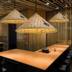 three lamps hanging over a wooden table in a room with bamboo partitions and chairs