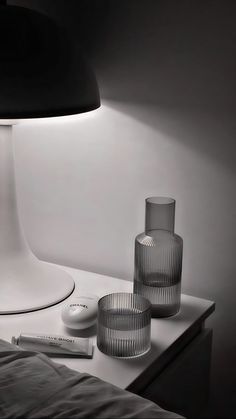 a lamp that is on top of a table next to two glasses and a remote control