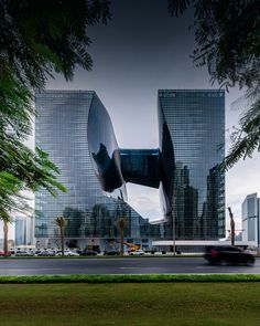 a car driving past some tall buildings in the middle of a city with cars passing by