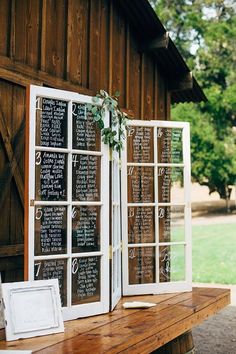 an old window is decorated with chalkboard and greenery for a rustic wedding ceremony