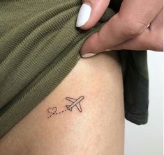 a woman with a small airplane tattoo on her thigh