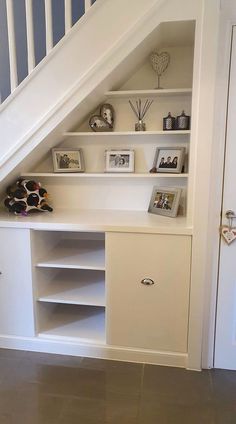 there is a shelf under the stairs with pictures and other items on it in this room