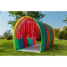 a colorful tent with red, green, blue and yellow curtains on it in the grass