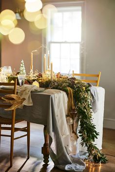 the table is decorated with greenery, candles and other things to decorate it for christmas