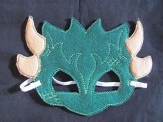 a green mask with horns on it sitting on top of a black cloth covered surface