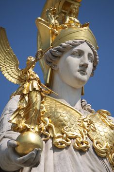 the statue is wearing a gold crown and holding a golden bird on its arm,