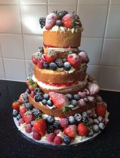 a triple layer cake covered in berries and other toppings on top of a counter