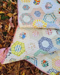 two quilts laying on the ground with leaves around them