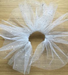 a white tulle with sequins on it sitting on top of a wooden table