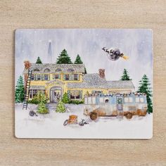 a coaster with a painting of a house in the snow and an airplane flying over it