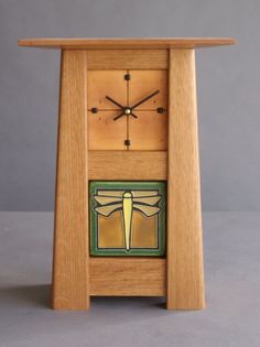 a wooden clock with an insect painted on the front and sides, sitting on a table