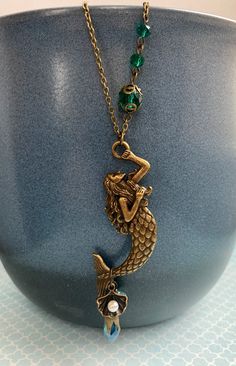 This+is+a+whimsical+necklace+with+a+large+mermaid+pendant.+There+is+a+teal+faceted+glass+bead,+a+glass+flower+bead+and+a+seashell+dangling+from+the+mermaid's+tail.+An+unusual+necklace,+handcrafted+by+Selma+Dreams+in+Finland. The+necklace+is+made+of+antiqued+brass,+all+parts+are+lead+and+nickel... Whimsical Mermaid, Whimsical Necklace, Large Mermaid, Teal Glass, Unusual Necklace, Mermaid Pendant, Mermaid Necklace, Small Gift Boxes, Mermaid Tail