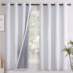 a white curtain hanging on the side of a window next to a potted plant