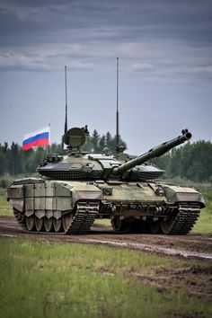 an army tank driving down a dirt road with a russian flag on it's side