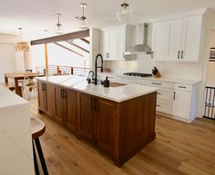 a large kitchen with white cabinets and wood flooring on the walls, along with an island in the middle