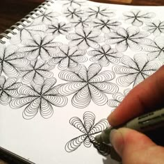 a hand is drawing an intricate design on a notebook