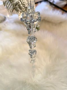 a crystal bird ornament sitting on top of a white fur covered floor next to a christmas tree