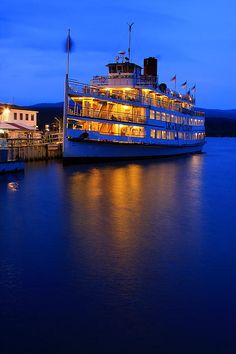 a large boat sitting on top of a lake next to a pier at night time