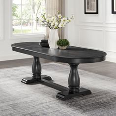 a black table sitting on top of a rug in front of a white vase filled with flowers