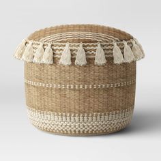 a large woven basket with tassels on top