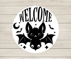 a sticker that says welcome with a bat and bats in the center on a wooden background