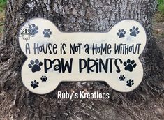 a dog bone sign that says, a house is not a home without paw prints