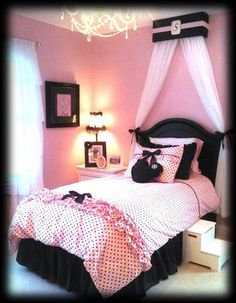 a bedroom with pink walls, black and white bedspread and chandelier