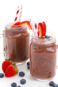 two mason jars with strawberries and blueberries on the side, one filled with chocolate pudding