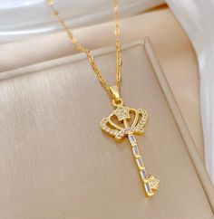 This stunning 18k Crown Key Crystal Necklace is the perfect way to add a touch of royal elegance to any ensemble. Its golden key pendant is delicately outlined in sparkling CZ stones for an eye-catching effect, while the ornate crown accent adds an understated hint of luxury. Wear your Crown Key necklace to add a sophisticated finish to any look. Elegant Gold Jewelry With Crown Design, Elegant Gold Crown Design Jewelry, Golden Key, Crown Necklace, Golden Crown, Luxury Wear, Key Necklace, Key Pendant, Cz Stone