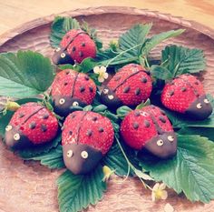 chocolate covered strawberries with leaves and flowers on a wooden platter, ready to be eaten