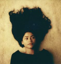 a woman laying down with her hair in the air