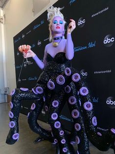 a woman dressed in black and purple is posing for the camera with an octopus like costume on