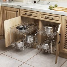 an open cabinet with pots and pans on the bottom shelf, in a kitchen