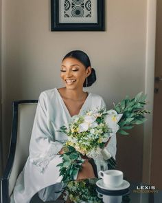 a woman sitting at a table with flowers in front of her and holding a bouquet