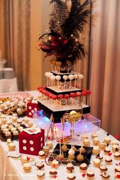 a table topped with lots of cupcakes covered in frosting and red decorations