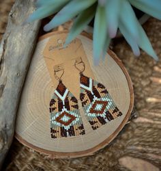 ⋄ Dive into the warm tones of the desert with these statement seed bead earrings. The earthy colors and geometric patterns evoke the rugged beauty of the Southwest, adding a touch of rustic charm to your ensemble. Make a statement with these unique handmade earrings! ⋄ ⋄⋄Over 1,300 individual beads used⋄⋄ Colors used: ⋄Dyed Matte Opaque Sienna ⋄Matte Espresso  ⋄Matte Opaque Glazed Cactus ⋄Matte Cream  ⋄Matte Opaque Light Terracotta Luster Materials used:  ⋄Miyuki Delica 11/0 Matte Seed Beads ⋄16mm Leverback Earwire ⋄Nymo Nylon Thread ⋄Beeswax to coat the thread Dimensions: ⋄Drop Length 2.25 inches ⋄Length 3 inches ⋄Width 1.25 inches Bohemian Brown Earrings As Gift, Bohemian Brown Earrings For Gift, Handmade Bohemian Brown Earrings, Handmade Brown Bohemian Earrings, Adjustable Brown Earrings With Colorful Beads, Handmade Brown Teardrop Beaded Earrings, Brown Bohemian Dangle Earrings, Artisan Brown Beaded Earrings For Pierced Ears, Brown Dangle Jewelry With Colorful Beads