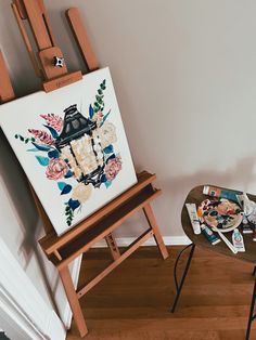 an easel sitting on top of a wooden floor next to a painting