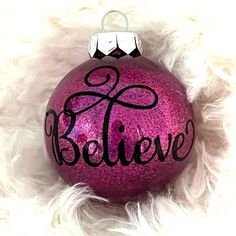 a pink ornament with the word believe on it