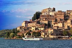 a boat is on the water in front of an old town that sits on top of a hill