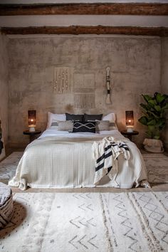 a bedroom with a large bed and two candles on the nightstands next to it