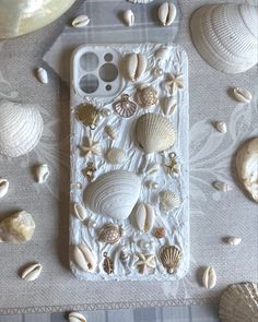 an iphone case with shells and seashells on the back, sitting on a table