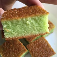 someone is holding up some green cake on a white plate with four pieces cut out