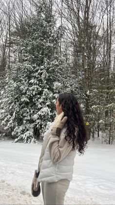 a woman standing in front of a snow covered tree with her back to the camera