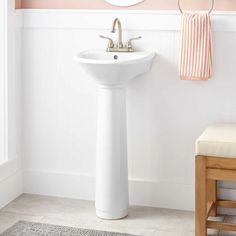 a white pedestal sink sitting next to a mirror in a pink and white bath room