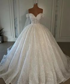 a white wedding dress on display in a room with a mannequin headdress