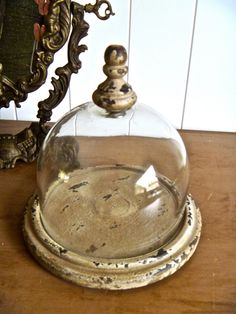 a glass dome sitting on top of a wooden table next to a mirror and clock