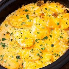 a crock pot filled with cheesy potatoes and garnished with parsley