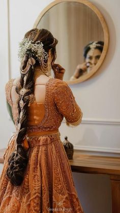 the back of a woman's head, wearing an orange dress and braided hair